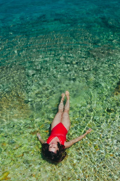 Denizde berrak ve şeffaf suda yatan kadın — Stok fotoğraf