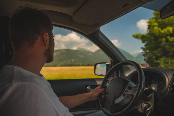 Mann fährt Auto und blickt auf Berge — Stockfoto