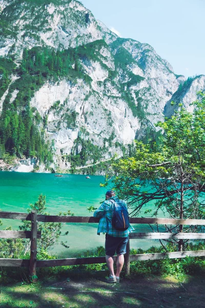 Muž s batohu, který se dívá na jezero v horách Dolomitů — Stock fotografie
