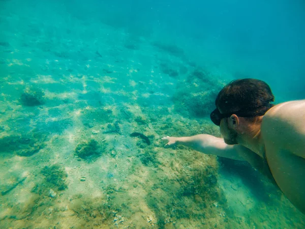 Hombre nadando bajo el agua con máscara conteniendo la respiración — Foto de Stock