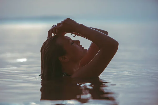 Femme dans l'eau de mer au coucher du soleil — Photo