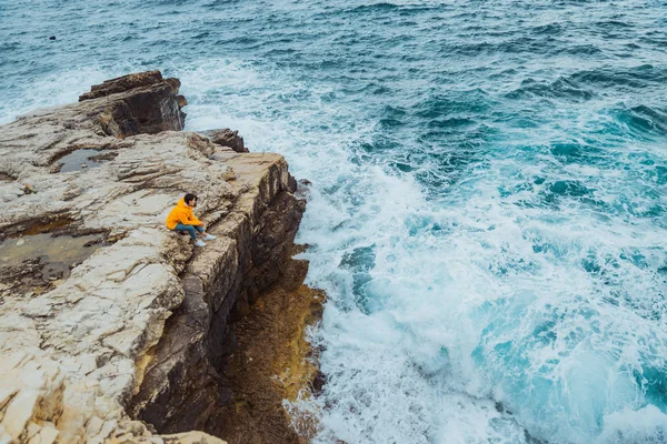 Femme assise sur le bord de la falaise regardant de grandes vagues — Photo