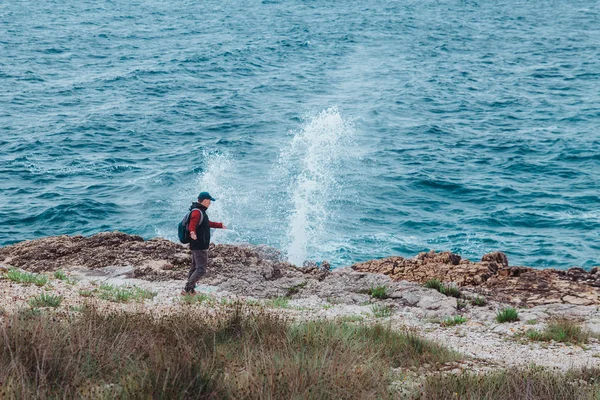 Homem andando pela praia do mar rochoso em tempo ventoso — Fotografia de Stock