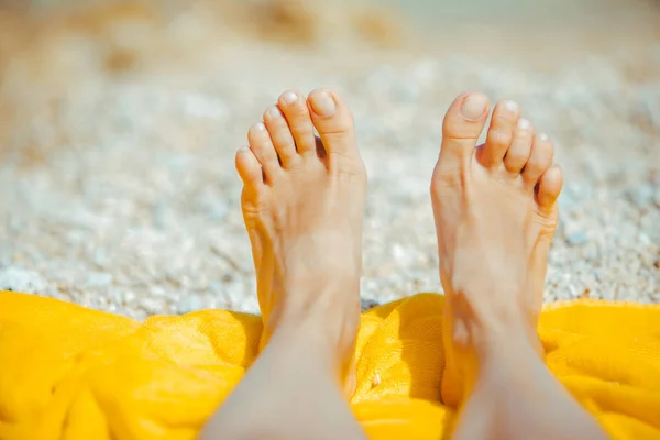 Pernas de mulher no cobertor amarelo na praia ensolarada de perto — Fotografia de Stock