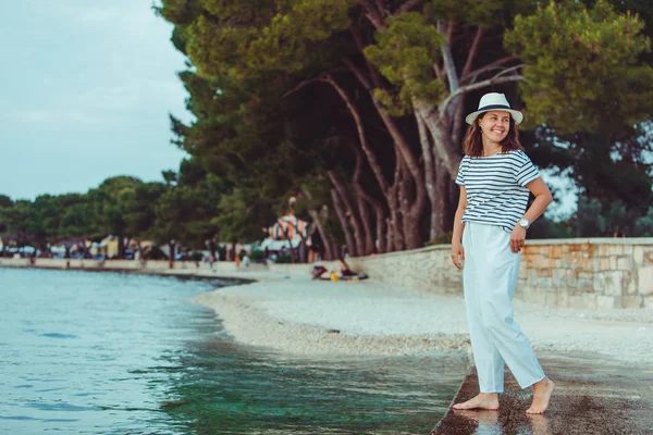 Frau in weißer Kleidung und Fedora-Hut am Strand des Meeres — Stockfoto