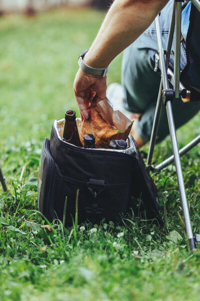 man hand taking chips from cooling bag with beer