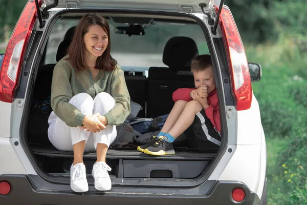 Young mother with kid boy sitting in car trunk resting in summer sunny day — Stock Photo, Image