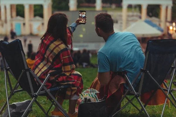 Casal tomando selfie no parque da cidade enquanto assiste filme no cinema ao ar livre — Fotografia de Stock