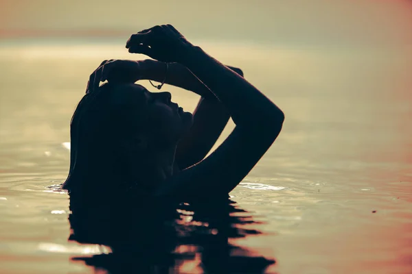 Mulher na água do mar ao pôr do sol — Fotografia de Stock