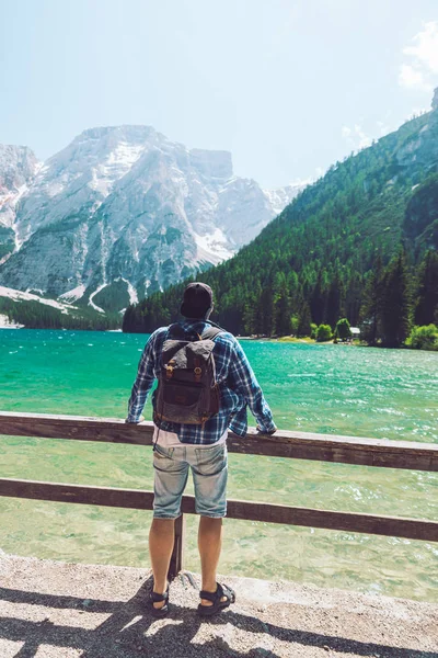 Hombre con mochila de pie mirando al lago en las montañas — Foto de Stock