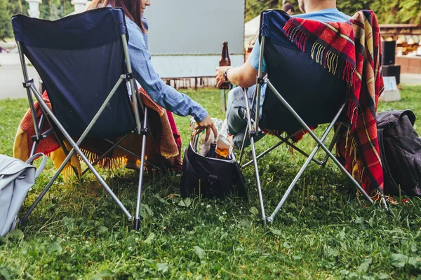 Par sitter i läger stolar i stadsparken ser filmen utomhus på Open Air Cinema — Stockfoto
