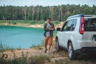 mavi su ile göle bakarak kenarında beyaz SUV araba yakın adam