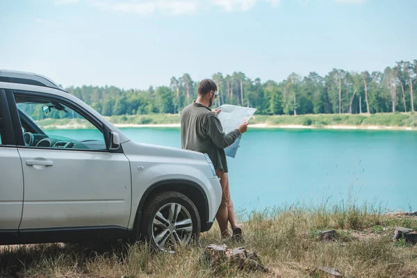 Homem do conceito do curso de carro que olha no homem no lago da capa do carro do SUV no fundo — Fotografia de Stock