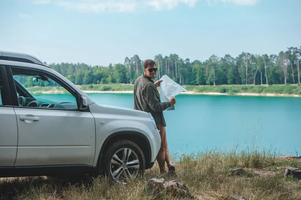 Homem do conceito do curso de carro que olha no homem no lago da capa do carro do SUV no fundo — Fotografia de Stock
