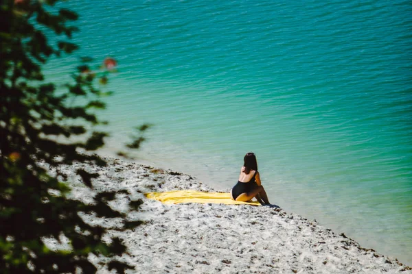 Vrouw zittend op zandstrand kijken naar blauw azuurblauwe water — Stockfoto