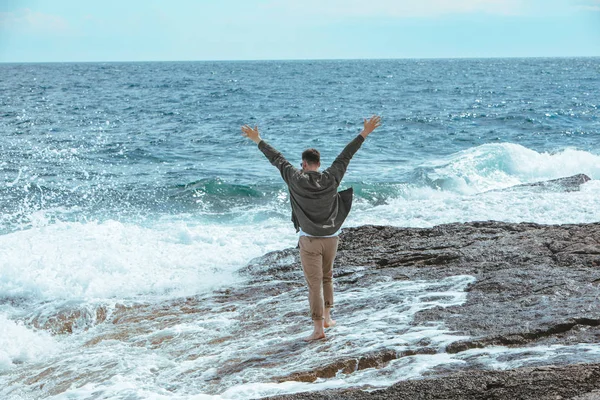 Homem andando pela praia rochosa em férias de verão dia ventoso. desfrutar de vista mar — Fotografia de Stock