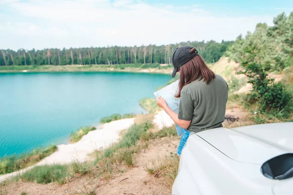 Ženská kontrola s mapou na vozu SUV jezero s modrou vodou na pozadí — Stock fotografie