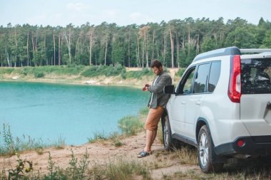 mavi su ile göle bakarak kenarında beyaz SUV araba yakın adam
