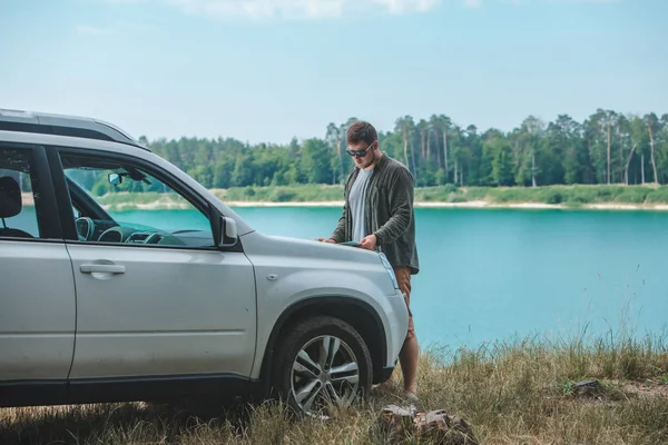 Η ιδέα για το ταξίδι του αυτοκινήτου που κοιτάζει τον άνθρωπο σε SUV λίμνη κουκούλα αυτοκίνητο στο παρασκήνιο — Φωτογραφία Αρχείου