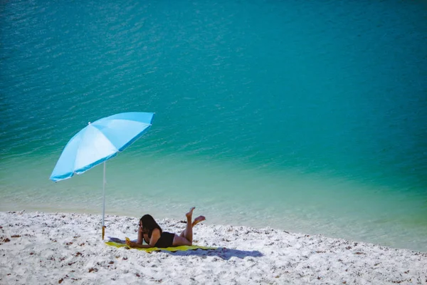 Frau im Badeanzug spazieren am Sandstrand Blauer Sonnenschirm und gelbe Decke — Stockfoto