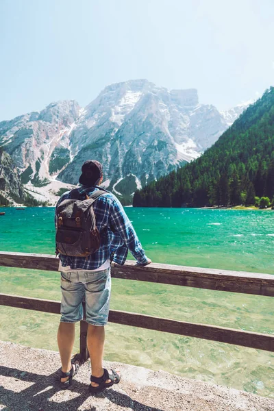 Hombre con mochila de pie mirando al lago en las montañas — Foto de Stock