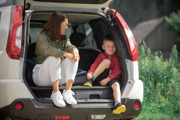 Young mother with kid boy sitting in car trunk resting in summer sunny day — Stock Photo, Image