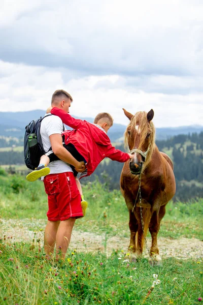 Мужчина с ребенком на фоне гор лошади — стоковое фото