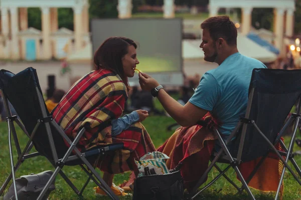屋外映画館で屋外で映画を見て、都市公園のキャンプチェアに座っているカップル — ストック写真