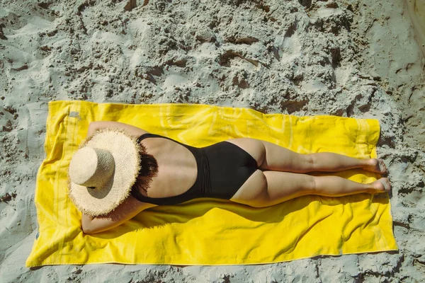 Vrouw zonnen op zandstrand leggen op gele deken — Stockfoto
