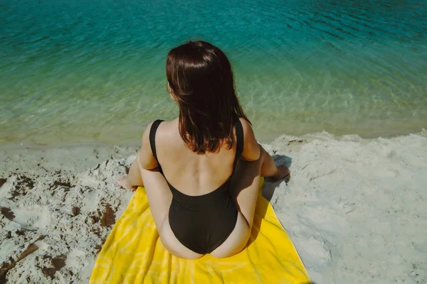 Mulher com sexy cuzinho sentado no amarelo cobertor em maiô na praia de areia — Fotografia de Stock