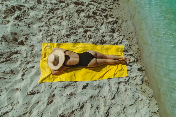 Vrouw zonnen op zandstrand leggen op gele deken — Stockfoto