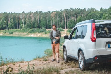 mavi su ile göle bakarak kenarında beyaz SUV araba yakın adam