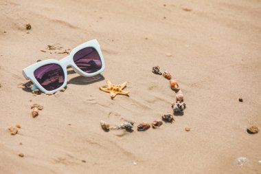 kabukları ve güneş gözlüğü ile kum çizilmiş gülümseme yüz