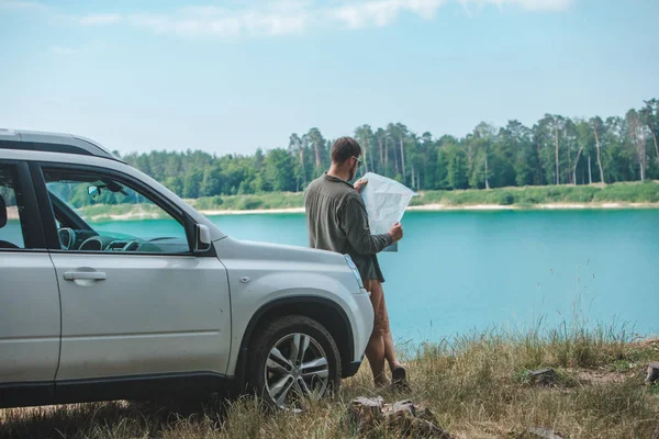 Homem do conceito do curso de carro que olha no homem no lago da capa do carro do SUV no fundo — Fotografia de Stock