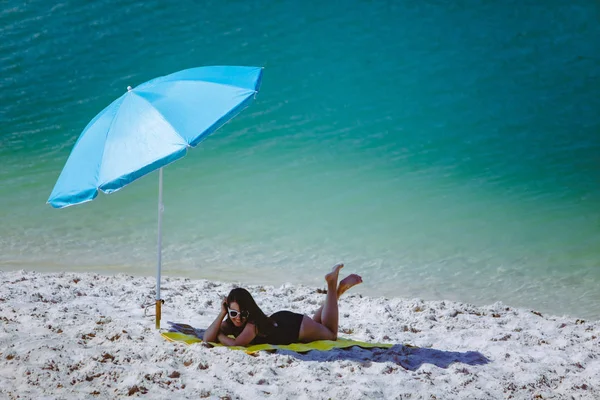 Frau im Badeanzug spazieren am Sandstrand Blauer Sonnenschirm und gelbe Decke — Stockfoto