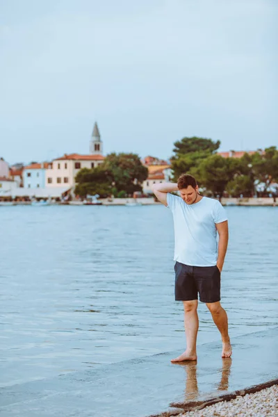 Ember sétál a tengeri strand nyáron este Fazana város háttérben Horvátországban — Stock Fotó