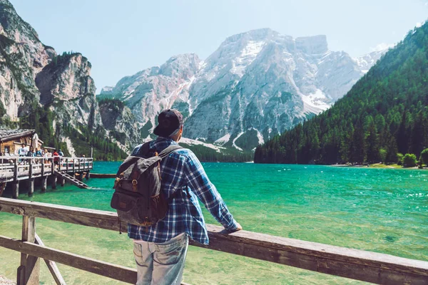 Hombre con mochila de pie mirando al lago en las montañas — Foto de Stock