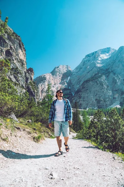 Güneşli bir gün dağlar patikadan yürüyen sırt çantası ile genç adam — Stok fotoğraf