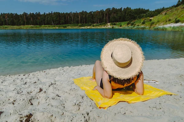 Frau liegt auf gelber Decke und sonnt sich am Sandstrand — Stockfoto