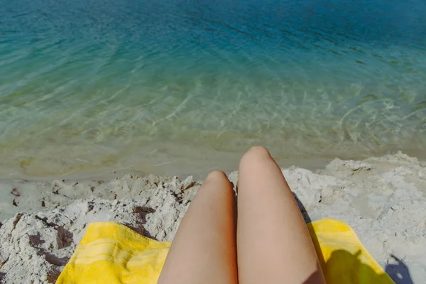 Point de vue femme jambes à la plage de sable en regardant l'eau claire bleue — Photo