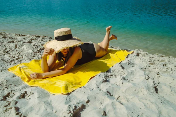 Žena pokládá na žlutou deku slunění na písečné pláži — Stock fotografie