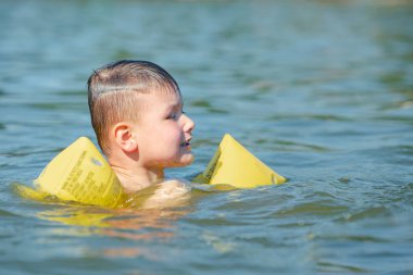şişme silah yardımları desteği ile gölde yüzen küçük yürümeye başlayan çocuk