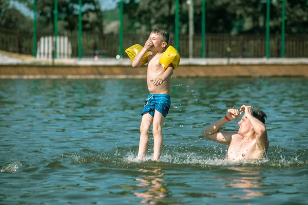 楽しみを持って水に息子を投げる父 — ストック写真
