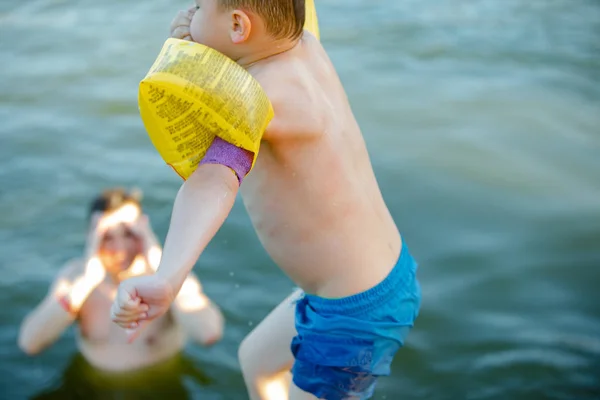Little kid jumping in water with air inflatable arms aids support — Stock Photo, Image
