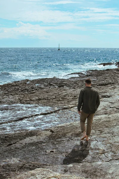 Homem andando pela praia rochosa em férias de verão dia ventoso. desfrutar de vista mar — Fotografia de Stock