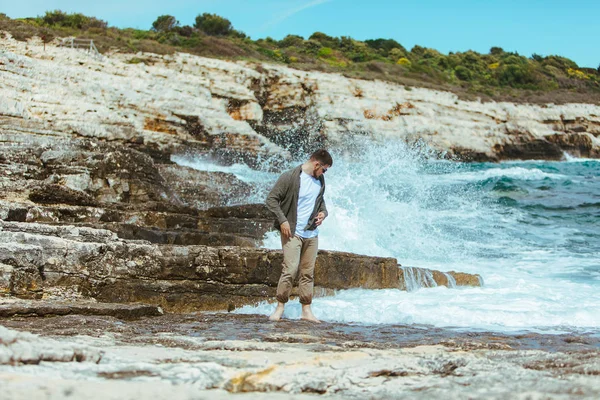 Homem andando pela praia rochosa em férias de verão dia ventoso. desfrutar de vista mar — Fotografia de Stock