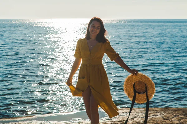 Ung ganska leende kvinna i gula sundress Walking by Stone Beach — Stockfoto