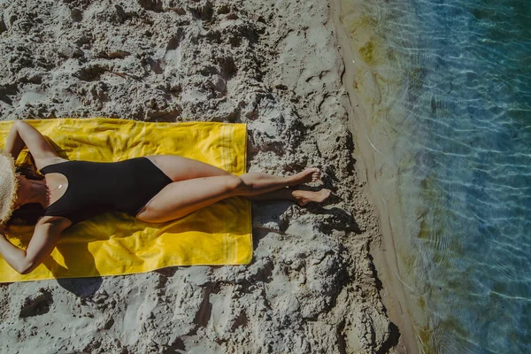 Frau sonnt sich an gelber Decke am Sandstrand — Stockfoto