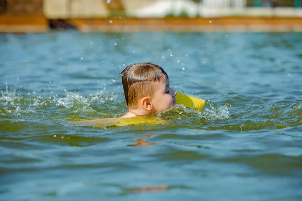 little toddler kid swimming in lake with inflatable arms aids support