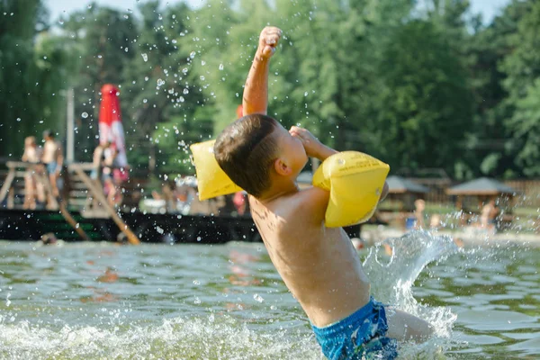 little toddler kid swimming in lake with inflatable arms aids support